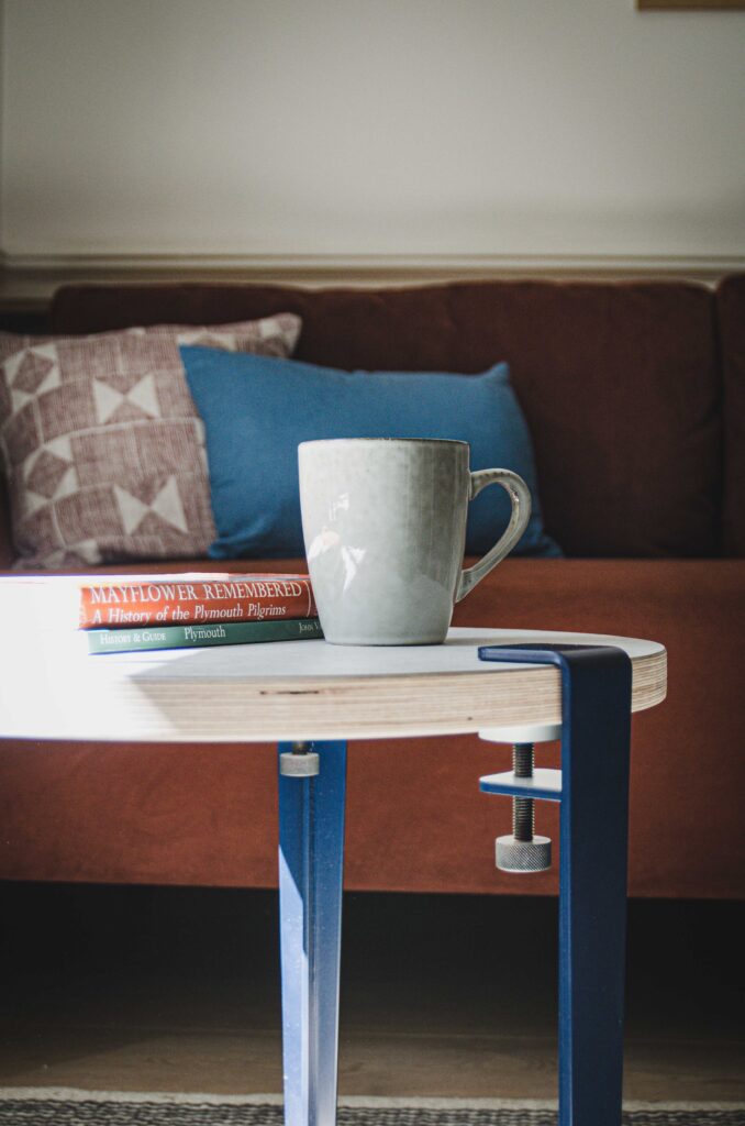 Blue coffee table legs from Tiptoe, coffee table with mug, sofa in background