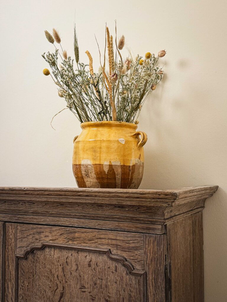 A yellow pot with a dried flower display
